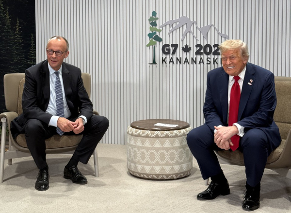 Germany’s chancellor and the U.S. president seated facing each other during a meeting at the G7 summit in Kananaskis, Canada, with the G7 2025 logo on the wall behind them