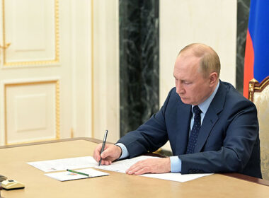 Russian President Vladimir Putin sits at a desk signing Presidential Decree