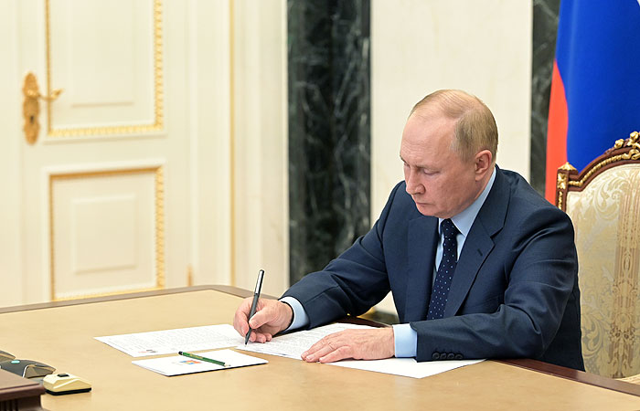 Russian President Vladimir Putin sits at a desk signing Presidential Decree