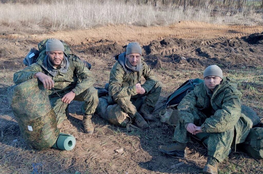 Foreign mercenaries in Russian military uniforms sitting on the ground with rucksacks