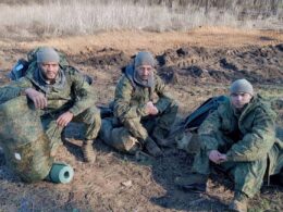 Foreign mercenaries in Russian military uniforms sitting on the ground with rucksacks