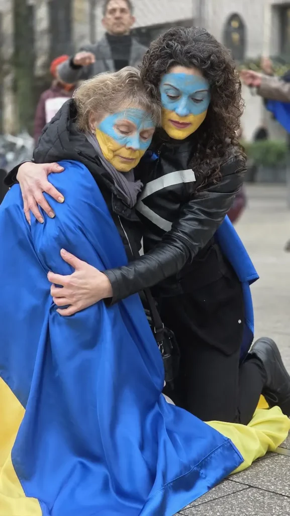 Ukrainian women rally blue yellow flag embrace sadness distress support