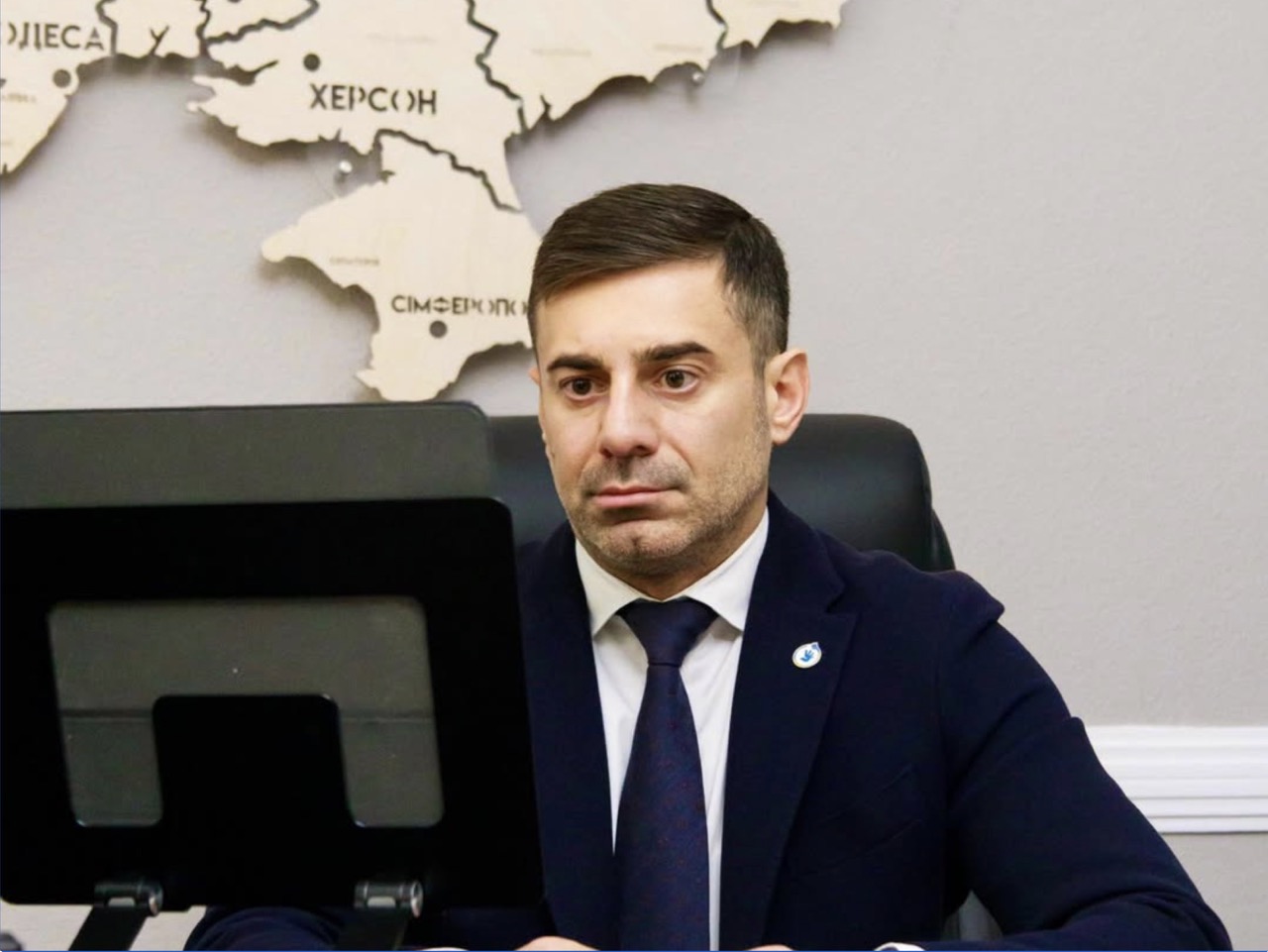 Ukrainian Ombudsman Dmytro Lubinets at his desk with a map of Ukraine behind him
