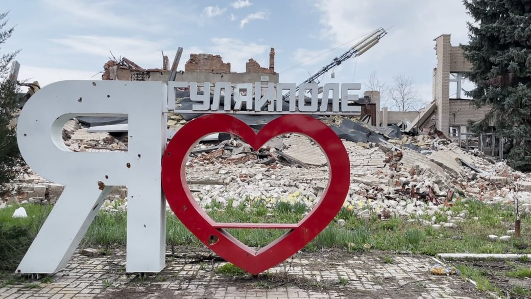 The "I ♥ Huliaipole" sign stands in front of destroyed buildings in Huliaipole, Zaporizhzhia Oblast