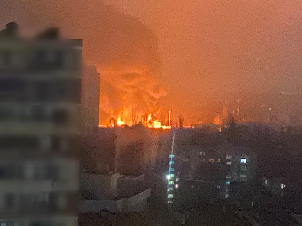 Fire burns on the Odesa skyline after Russian drone and missile strikes on 13 December 2025, viewed from a residential apartment building