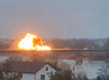 Explosion and fireball on a bridge over the Dniester river, with a residential house in the foreground and gray winter sky