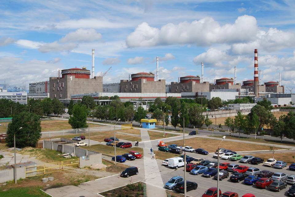 Zaporizhzhia Nuclear Power Plant with three reactor units visible, parking lot in foreground