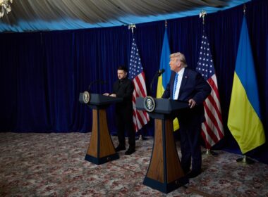 Volodymyr Zelenskyy and Donald Trump stand at podiums during a joint press conference at Mar-a-Lago, with US and Ukrainian flags behind them