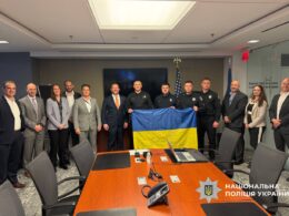 Ukrainian police officers in uniform hold a Ukrainian flag alongside American officials in a Washington conference room