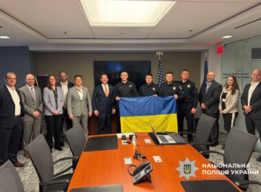 Ukrainian police officers in uniform hold a Ukrainian flag alongside American officials in a Washington conference room