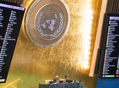 Electronic voting boards display country-by-country votes during a UN General Assembly session on Ukraine, with the UN emblem visible in the center of the hall