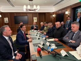 US and Ukrainian officials seated across a conference table during Florida peace talks, with Reuters and Ukrainian media microphones visible in foreground