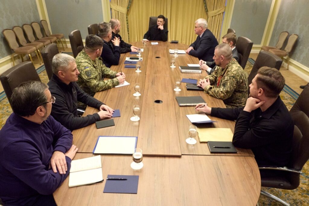 Ukrainian President Volodymyr Zelenskyy meets with his negotiating delegation around a conference table, including military officials in uniform and civilian advisors, during a briefing on US peace talks, 02 December 2025
