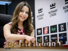 Ukrainian chess player and commentator Angelika Valkova smiling at a chessboard during Norway Chess tournament