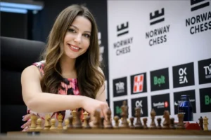 Ukrainian chess player and commentator Angelika Valkova smiling at a chessboard during Norway Chess tournament