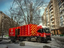 Red industrial generator truck connected to a Kyiv apartment building in winter, providing emergency power during blackouts