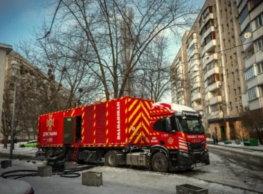 Red industrial generator truck connected to a Kyiv apartment building in winter, providing emergency power during blackouts
