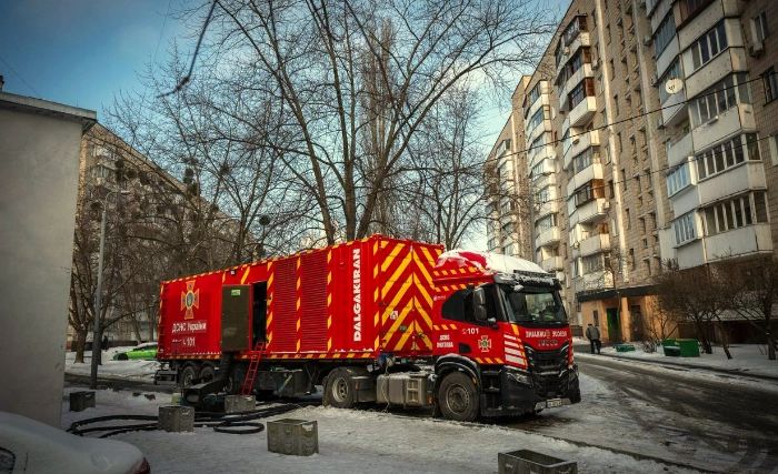 Red industrial generator truck connected to a Kyiv apartment building in winter, providing emergency power during blackouts