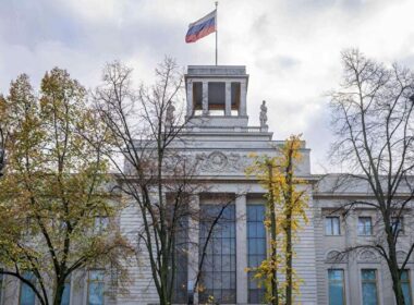 The Russian Embassy building in Berlin with the Russian flag flying on top, partially obscured by autumn trees