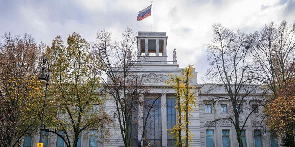 The Russian Embassy building in Berlin with the Russian flag flying on top, partially obscured by autumn trees