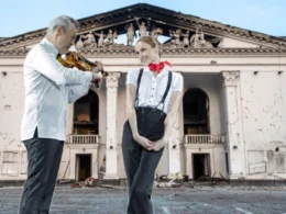 Composite photo showing violinist Vadim Repin and ballerina Svetlana Zakharova performing in front of the war-damaged Mariupol Drama Theater, its facade scarred by shelling and roof partially destroyed.
