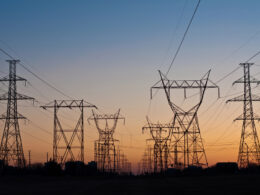 Nordic energy infrastructure power grid transmission towers silhouetted against sunset sky