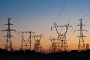 Nordic energy infrastructure power grid transmission towers silhouetted against sunset sky