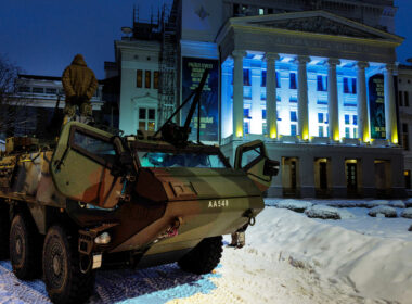 €500000 60 seconds — latvians buying robots get wounded soldiers out drone kill zones · post military armored vehicle front latvian national opera lit ukrainian flag colors ahead aizved mani