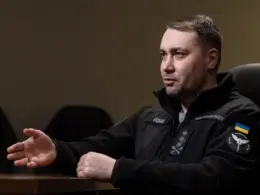 Kyrylo Budanov, head of Ukraine's Office of the President, gestures while speaking during an interview, wearing a black fleece marked with his name and the HUR insignia.