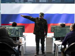 Russian army officer supervising cyber attacks on state networks, spreading misinformation and fake news around Europe during hybrid war. Military personnel works on scams and hacking. Russian disinformation misinformation cyber campaign Russian information warfare