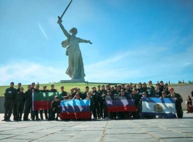Ukrainian teenagers in Avangard camp uniforms pose with flags of four Russian-occupied Ukrainian regions in front of the Motherland Calls statue at Mamayev Kurgan in Volgograd