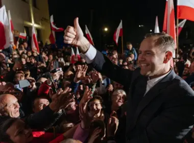 Karol Nawrocki gives a thumbs-up to a crowd waving Polish flags on his presidential election night.