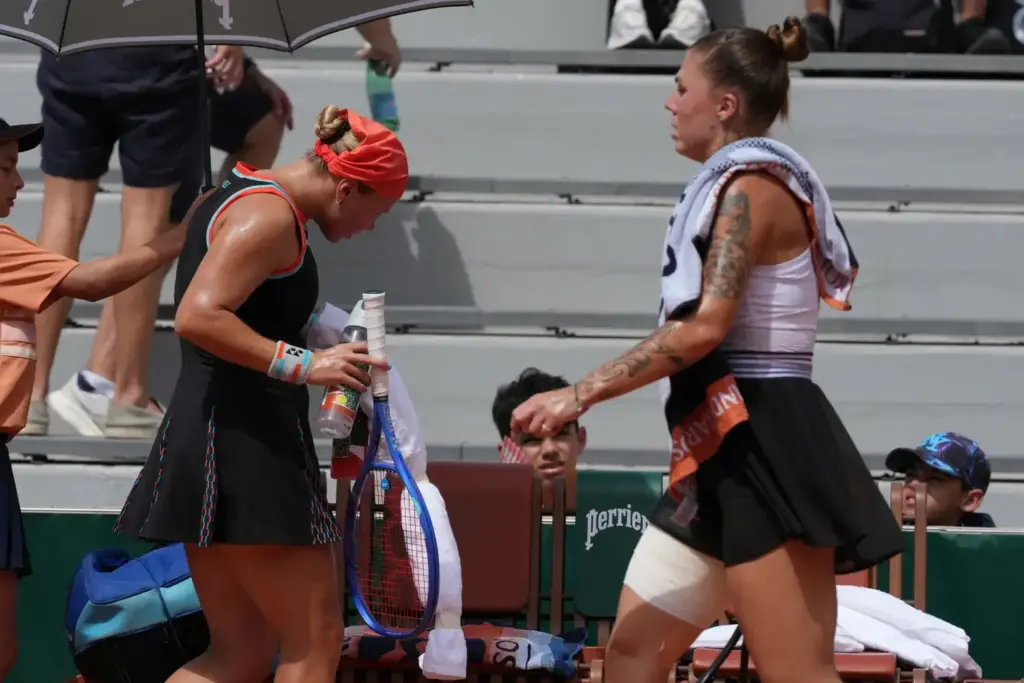 Diana Shnaider of Russia, left, and Oleksandra Oliynykova of Ukraine change sides during their third round women's singles tennis match at the French Open tennis tournament in Paris, Saturday, May 30, 2026. 
