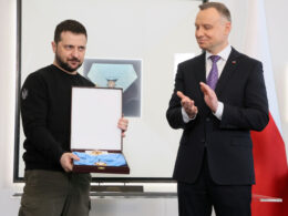 Volodymyr Zelenskyy holds the Order of the White Eagle in its case as Polish President Andrzej Duda applauds at the Presidential Palace in Warsaw, April 2023
