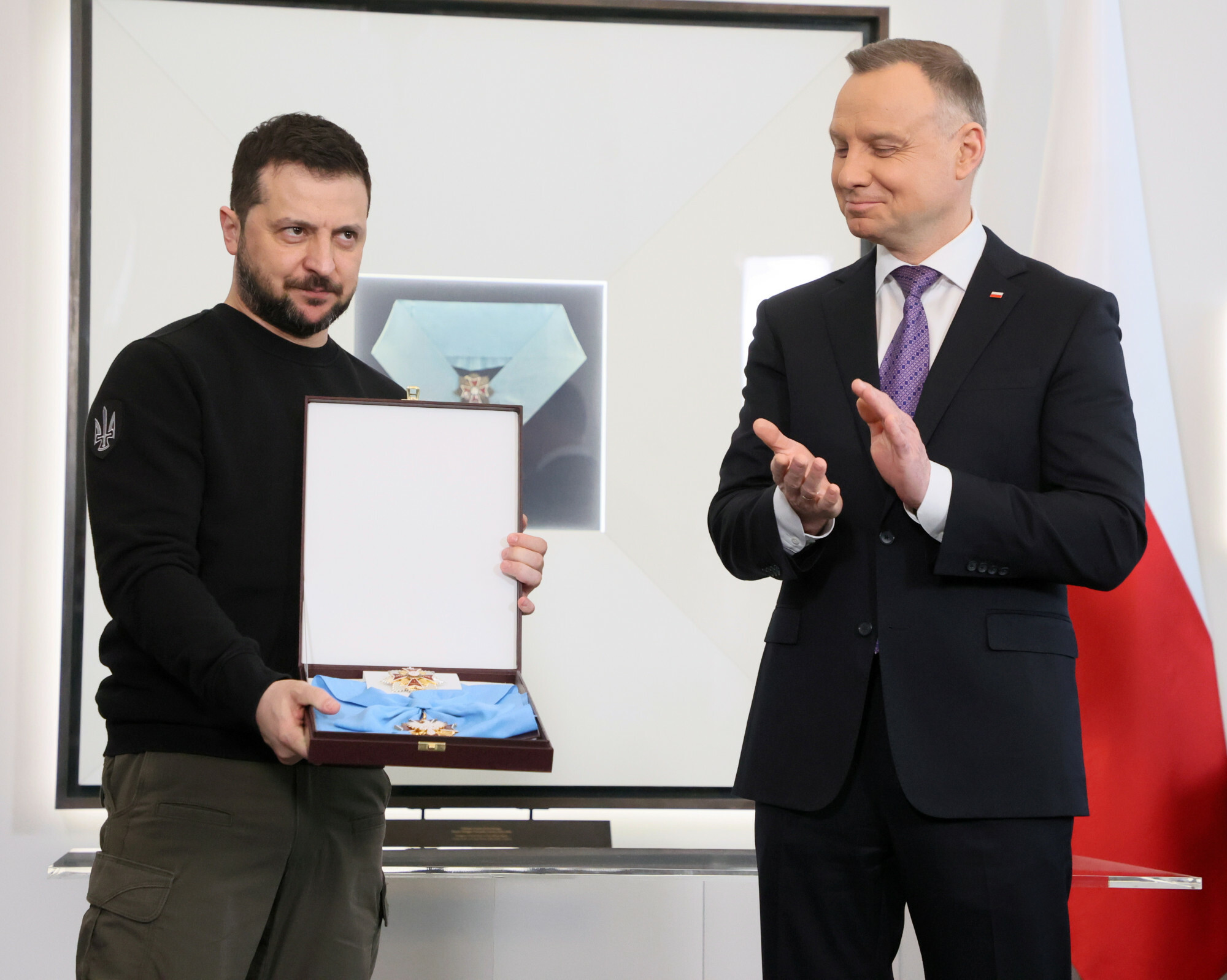 Volodymyr Zelenskyy holds the Order of the White Eagle in its case as Polish President Andrzej Duda applauds at the Presidential Palace in Warsaw, April 2023