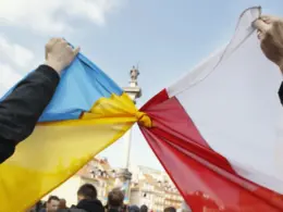 Demonstrators knot a Ukrainian flag and a Polish flag together at a rally in Warsaw's Castle Square