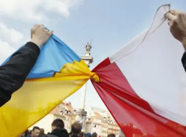 Demonstrators knot a Ukrainian flag and a Polish flag together at a rally in Warsaw's Castle Square
