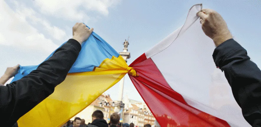 Demonstrators knot a Ukrainian flag and a Polish flag together at a rally in Warsaw's Castle Square