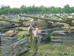 Rows of T-72A/T-72B-family tanks in long-term storage, with spare armor and track components piled nearby.