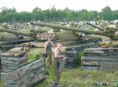 Rows of T-72A/T-72B-family tanks in long-term storage, with spare armor and track components piled nearby.