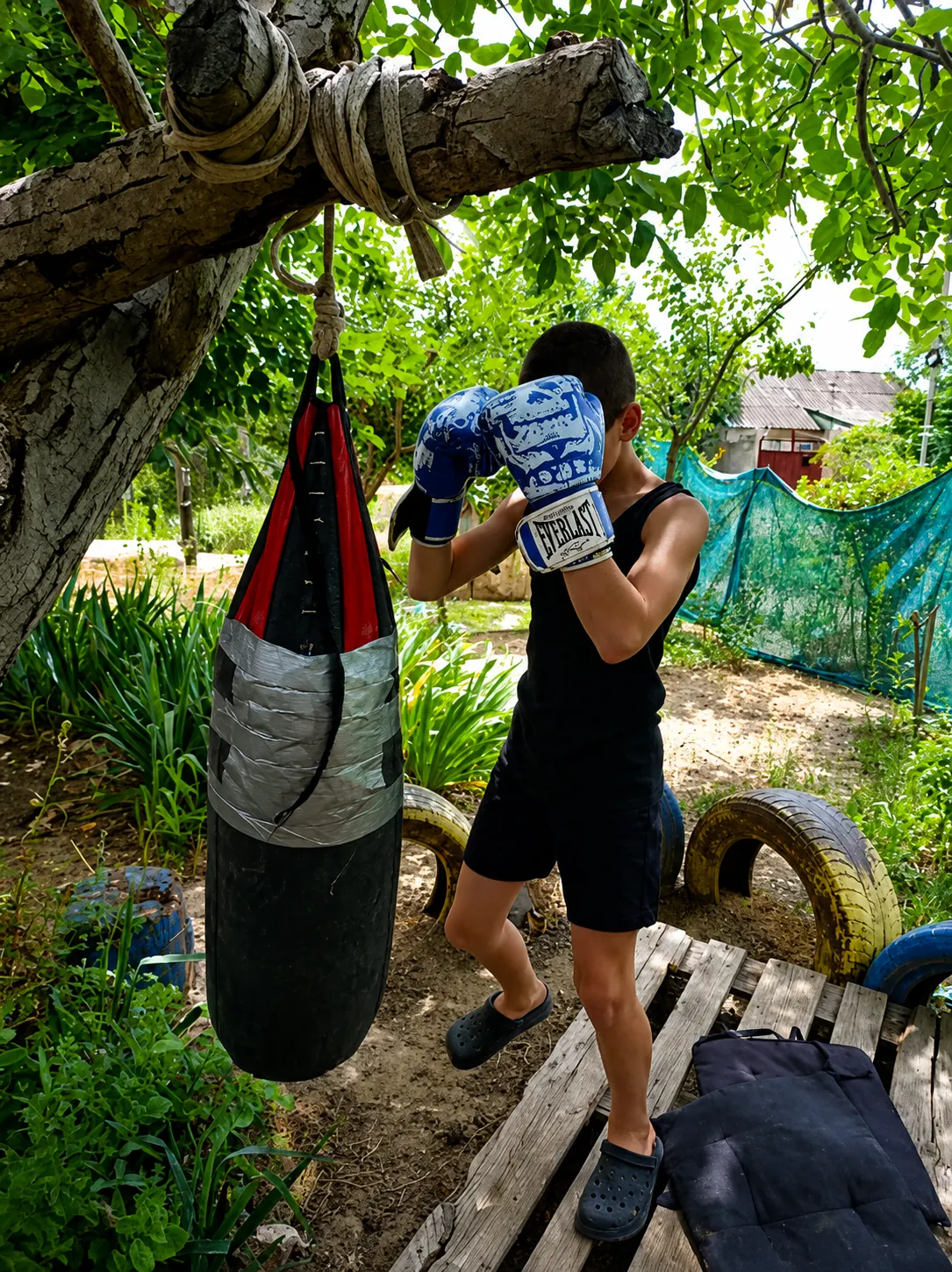 Young boxer Timur with the punching bag he trains on at home in Kherson