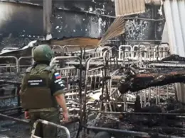 olenivka officials taganrog jail land eu sanctions list abuse ukrainian prisoners · post so-called investigator russia's investigative committee stands among burned bunk beds destroyed barrack prison where russians killed war
