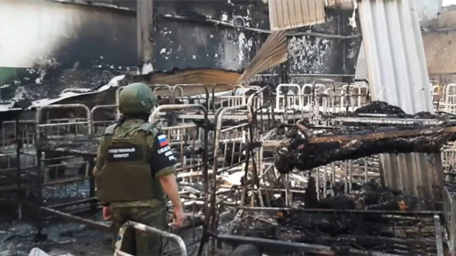 olenivka officials taganrog jail land eu sanctions list abuse ukrainian prisoners · post so-called investigator russia's investigative committee stands among burned bunk beds destroyed barrack prison where russians killed war