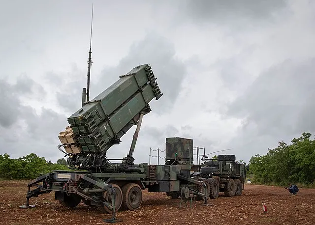 A Patriot air defense launcher raised into firing position on a military trailer.
