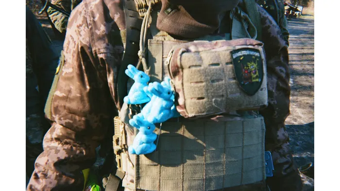 Small blue figurines are attached to a Ukrainian service member’s body armor, 2025. Photo: project participant Danylo “Doc”