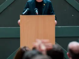 UK Prime Minister Andy Burnham speaks at a lectern before an audience.
