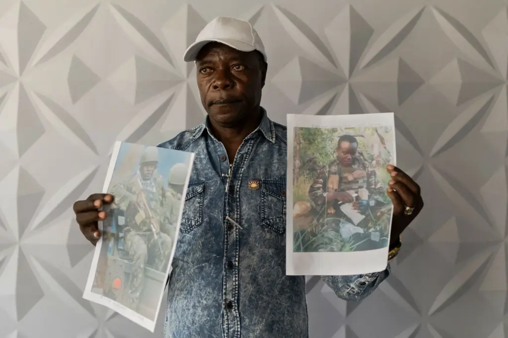 A Kenyan man holds two printed photographs of his son killed fighting for Russia.