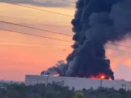 Thick black smoke and flames rise from an Ozon warehouse in Chapayevsk, Russia, at sunset.