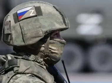 Russian soldier in camouflage wearing a helmet marked with the Russian flag and “Z” symbol.