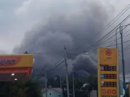 Thick gray smoke rises behind buildings, power lines, and a fuel station in Samara after a reported missile strike.